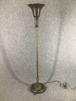 Stehlampe mit gedrehtem Messingstandfuß und schalenförmigem, dunkel getöntem Lampenschirm. Die Lampe steht auf einem runden Sockel mit kleinen Füßen
