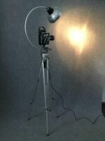 Vintage Filmkamera auf einem stabilen Stativ, kombiniert mit einer Bogenlampe für eine gleichmäßige Beleuchtung.