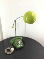 Grünes Retro-Wählscheibentelefon mit integrierter Schreibtischlampe im klassischen Stil. Perfekt für ein nostalgisches Ambiente auf dem Schreibtisch oder Sideboard