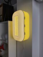 Wandlampe im Retro-Stil mit einem leuchtend gelben Gehäuse und einem rechteckigen Lichtfenster. Das Design erinnert an die 70er-Jahre und bringt Vintage-Charme in jeden Raum