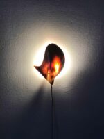 Wandleuchte mit organischer, muschelförmiger Struktur, die ein warmes, indirektes Licht an die Wand wirft