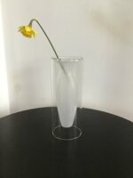 Glasvase mit elegant geschwungener Form, in der eine einzelne gelbe Blume stilvoll arrangiert ist