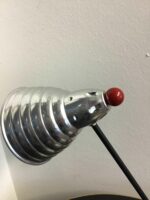 Nahaufnahme des silbernen Lampenschirms mit roten Akzenten, der auf einem schlanken schwarzen Stab montiert ist