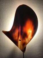Detailansicht der Wandleuchte mit schimmernder, muschelförmiger Struktur, die ein warmes Licht abstrahlt