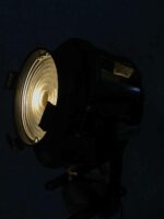 Nahaufnahme eines eingeschalteten Studioscheinwerfers, das weiche Licht durch die Glaslinse strahlt in einem dunklen Raum