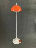 Gesamtdarstellung der Stehlampe mit rotem Schirm, weißem Standfuß und orangem Kabel, vor grauem Hintergrund