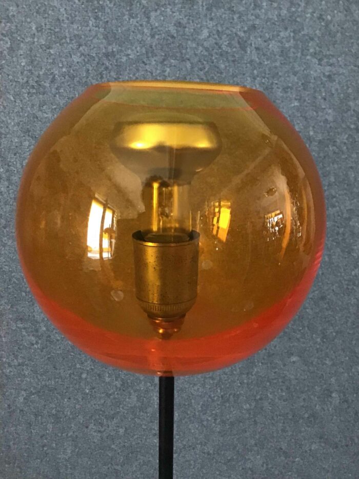 Detaillierte Nahaufnahme einer Glaskugel-Leuchte mit bernsteinfarbenem Glas und einem antik anmutenden Leuchtmittel, das für warmes und angenehmes Licht sorgt