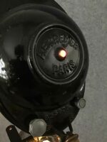 Detailaufnahme der Rückseite eines schwarzen Studioscheinwerfers mit der Aufschrift ‚AE Cremer Paris‘ und roten Lampen
